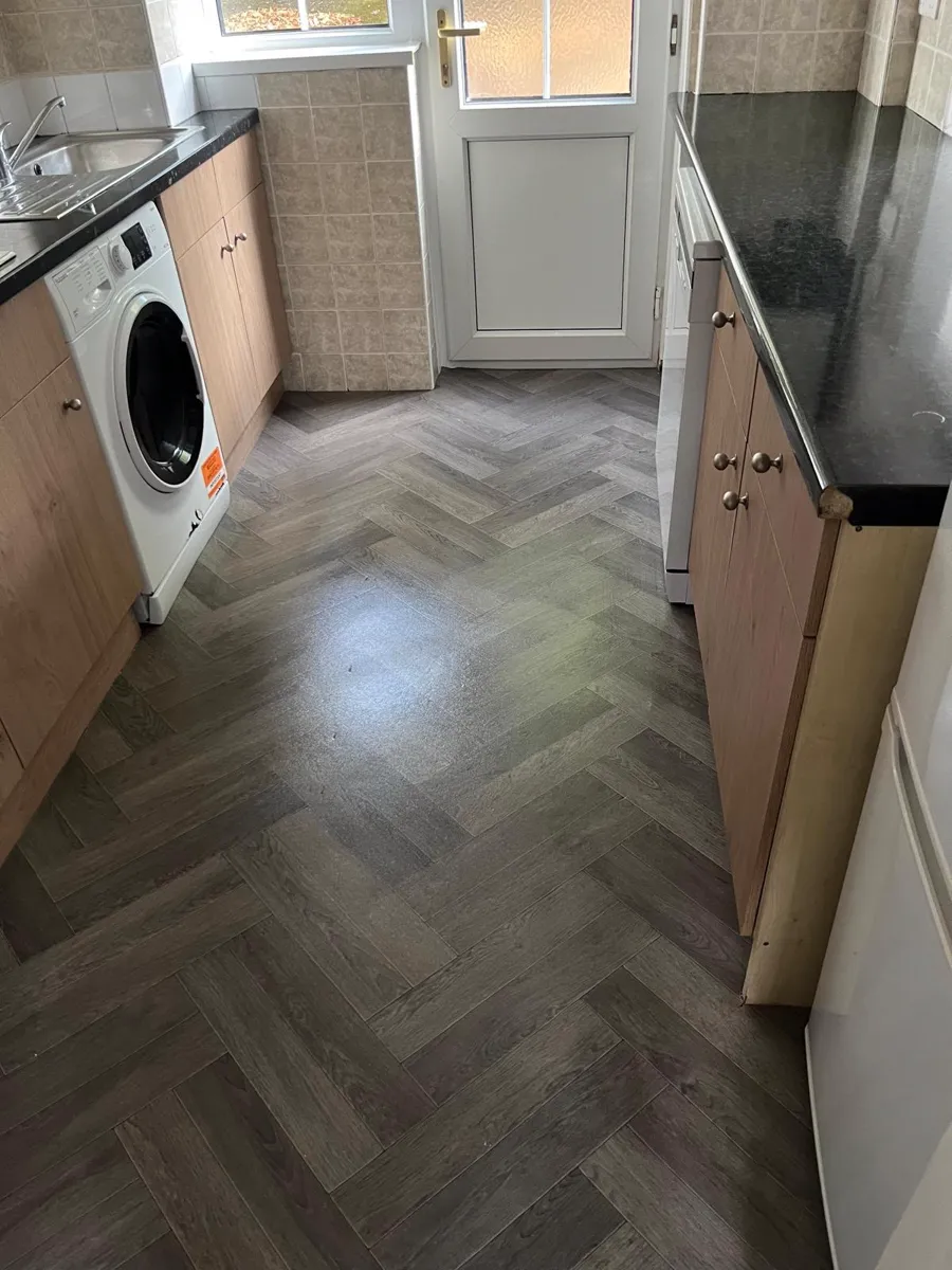 Clean galley kitchen with washing machine and herringbone floor