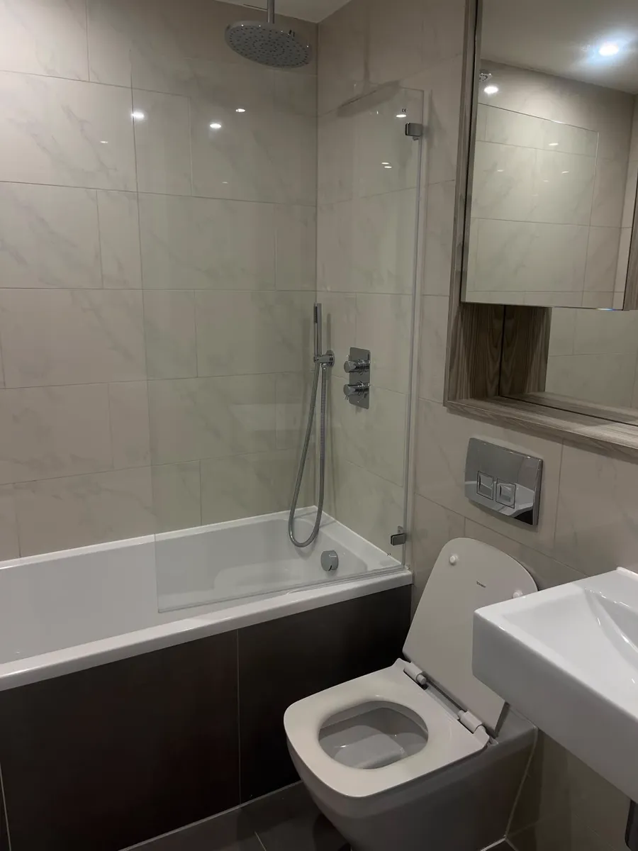 Clean bathroom with bath, glass screen, toilet and basin