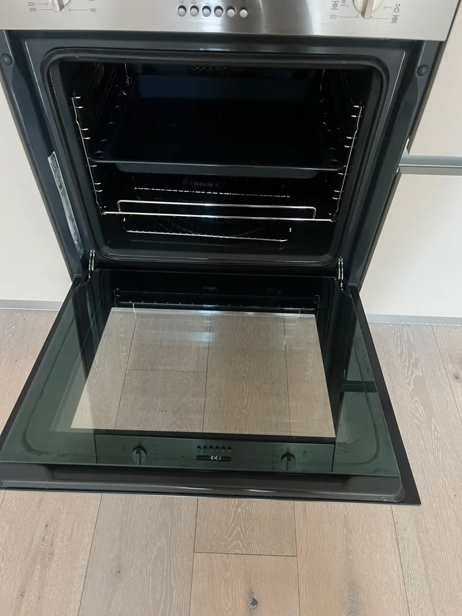 Built-in oven after cleaning with clean interior, shelves, tray and door glass