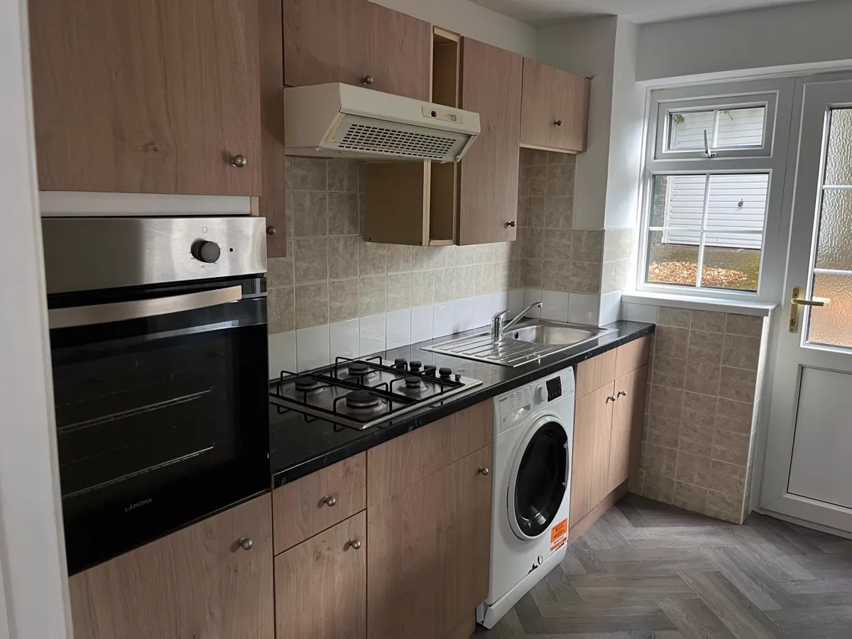 Clean kitchen with built-in oven, gas hob and extractor hood